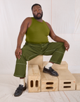 Elijah is wearing Railroad Carpenter Jeans in Summer Olive and summer olive Muscle Tee