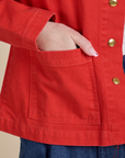 Close up of Hana's hand in the front pocket of Denim Work Jacket in Mustang Red