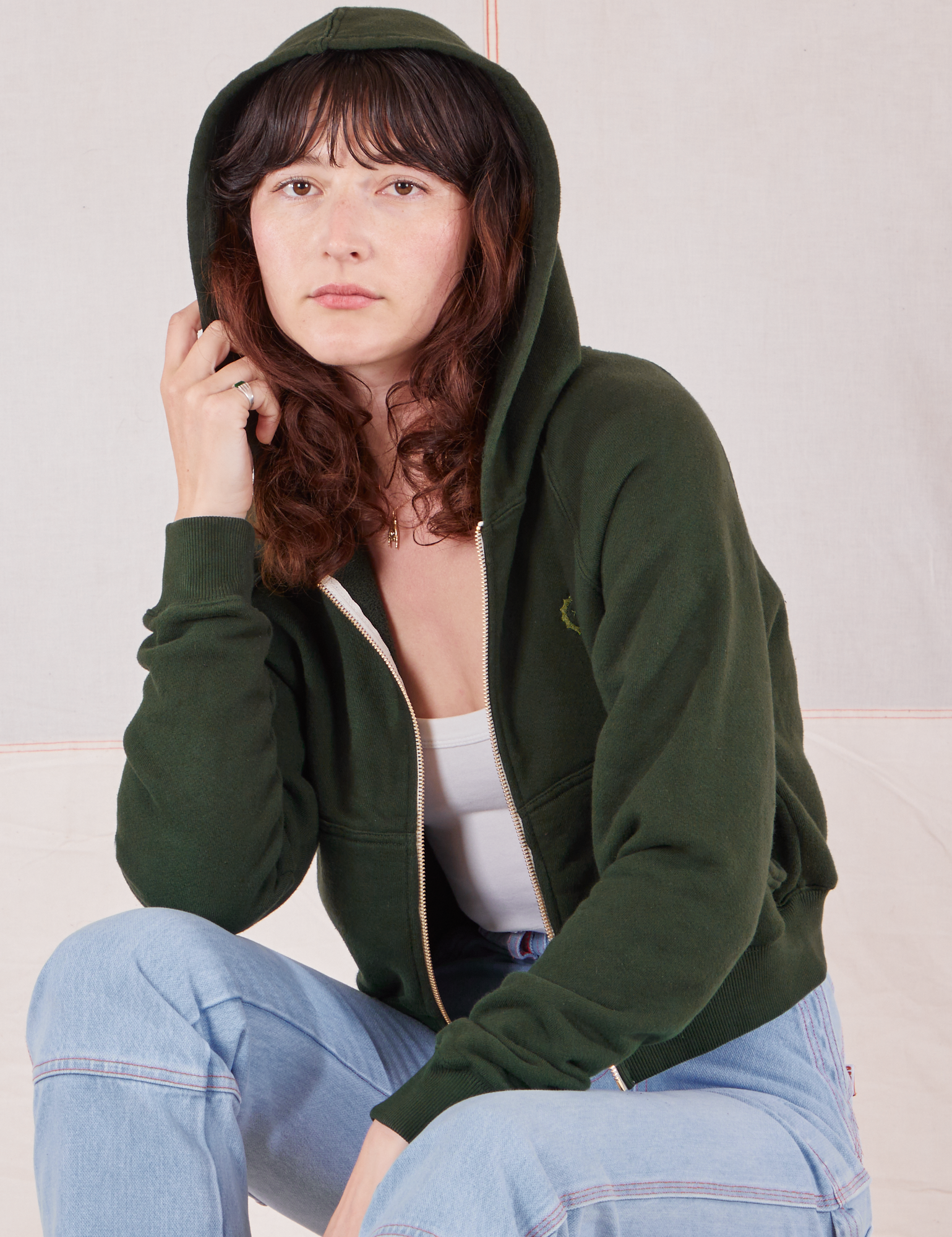 Alex is wearing Cropped Zip Hoodie in Swamp Green with the hood over her head