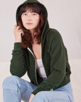 Alex is wearing Cropped Zip Hoodie in Swamp Green with the hood over her head