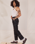 Side view of Carpenter Jeans in Black and Tank Top in vintage tee off-white worn by Jesse