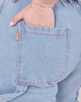 Back pocket close up of Carpenter Jeans in Light Wash. Ashley has her hand tucked into the pocket.