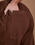 Close up of Alex's hand in the back pocket of Drop Pocket Cargo Pants in Fudgesicle Brown