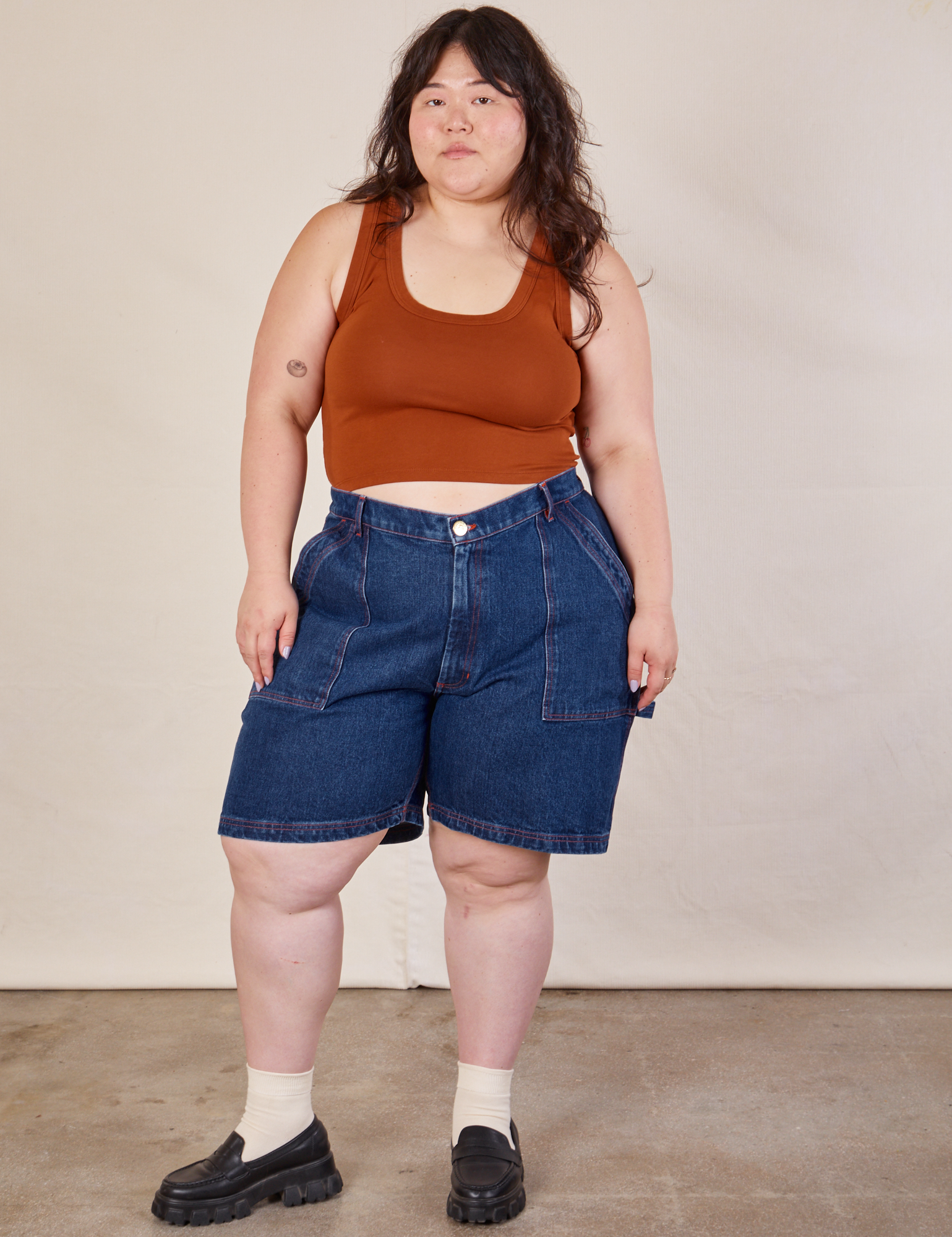 Ashley is 5'7" and wearing 1XL Carpenter Shorts in Dark Wash paired with burnt terracotta Cropped Tank