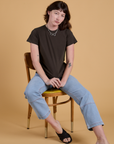 Alex is wearing Organic Vintage Tee in Espresso Brown and light wash Carpenter Jeans and sitting in a chair