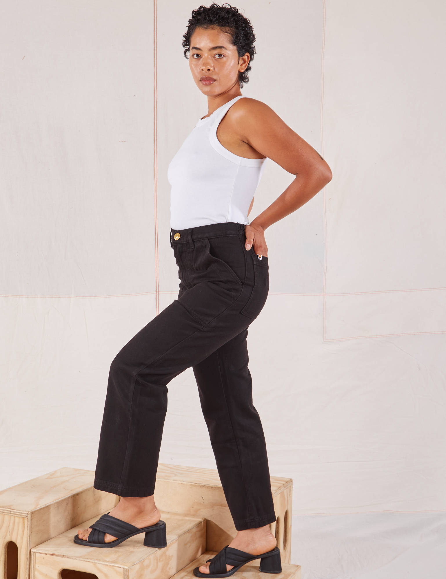 Side view of Organic Work Pants in Basic Black and Racerback Tank in vintage tee off-white on Mika