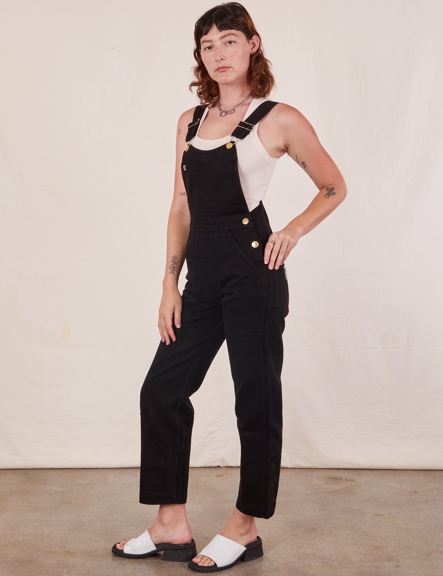 Angled view of Original Overalls in Mono Black and Cropped Tank Top in vintage tee off-white  worn by Alex