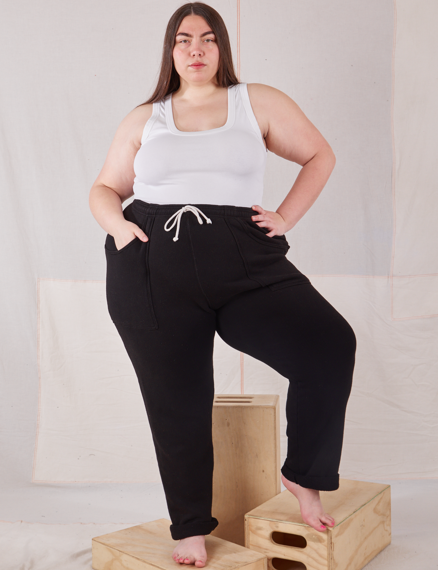 Marielena is 5&#39;8&quot; and wearing 1XL Rolled Cuff Sweat Pants in Basic Black paired with Cropped Tank in vintage tee off-white 