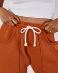 Rolled Cuff Sweat Pants in Burnt Terracotta front close up. Kandia is holding the waistband.