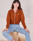 Alex is wearing Cropped Zip Hoodie in Burnt Terracotta and light wash Carpenter Jeans