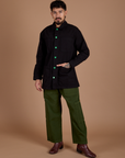 Jesse is wearing a buttoned up Ripstop Field Coat in Basic Black paired with evergreen Drop Pocket Cargo Pants