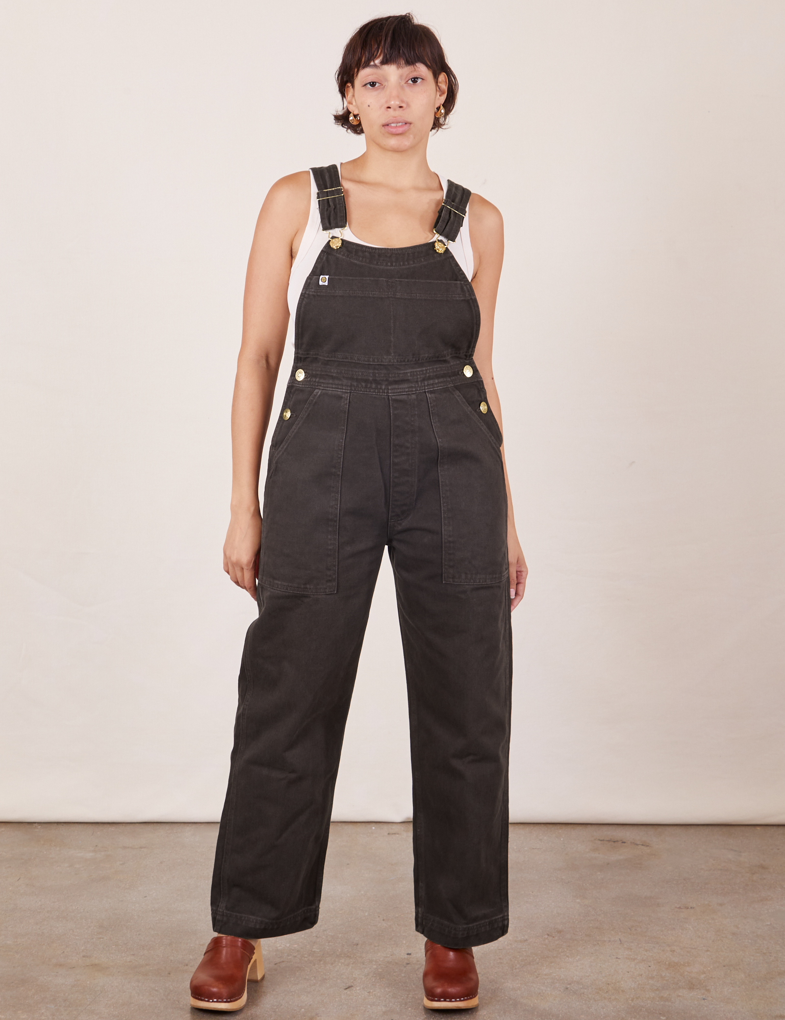 Tiara is 5&#39;4&quot; and wearing size XS Original Overalls in Mono Espresso with a Cropped Tank Top in vintage tee off-white underneath.