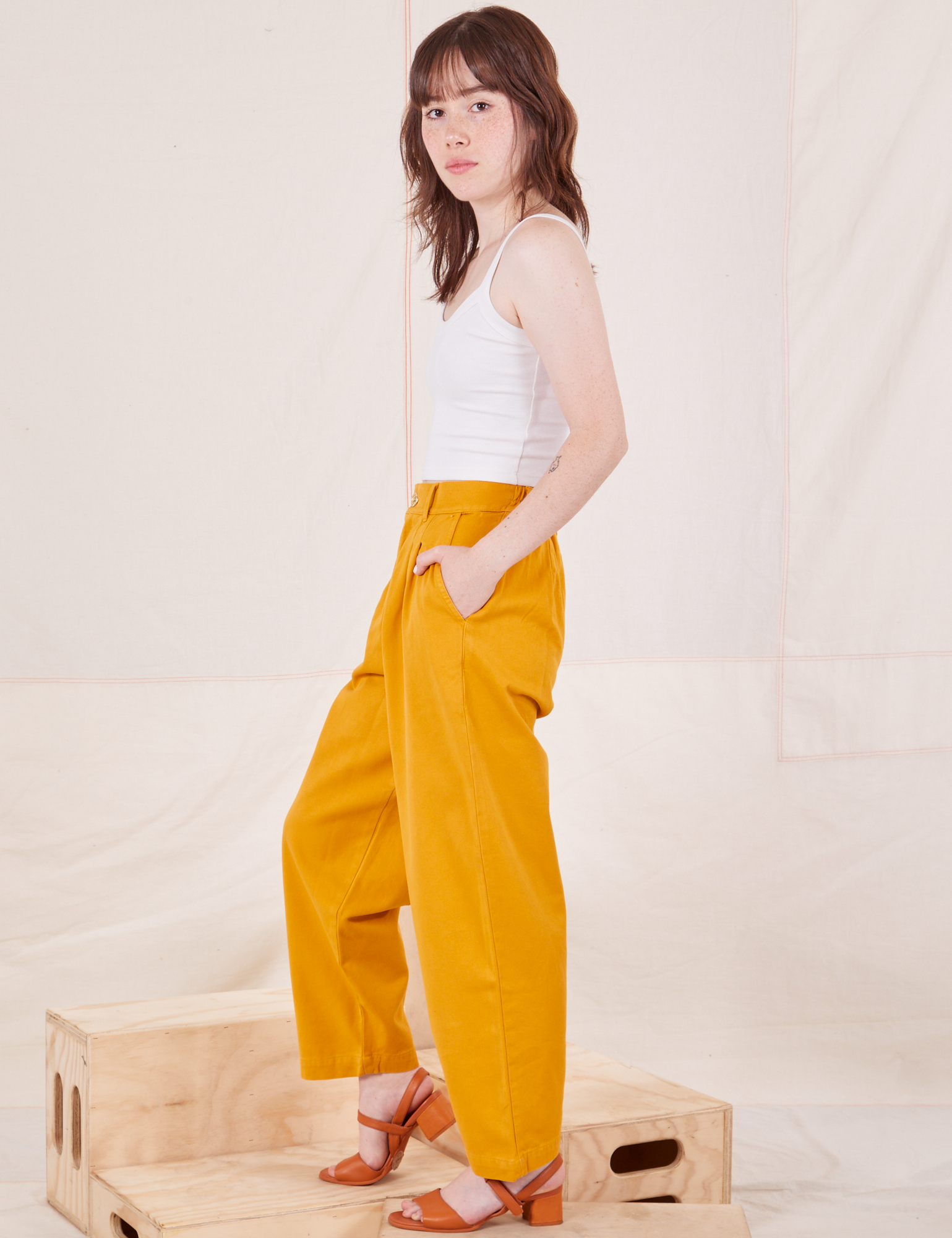 Side view of Organic Trousers in Mustard Yellow and Cropped Cami in vintage tee off-white worn by Hana