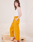 Side view of Organic Trousers in Mustard Yellow and vintage off-white Cami worn by Hana