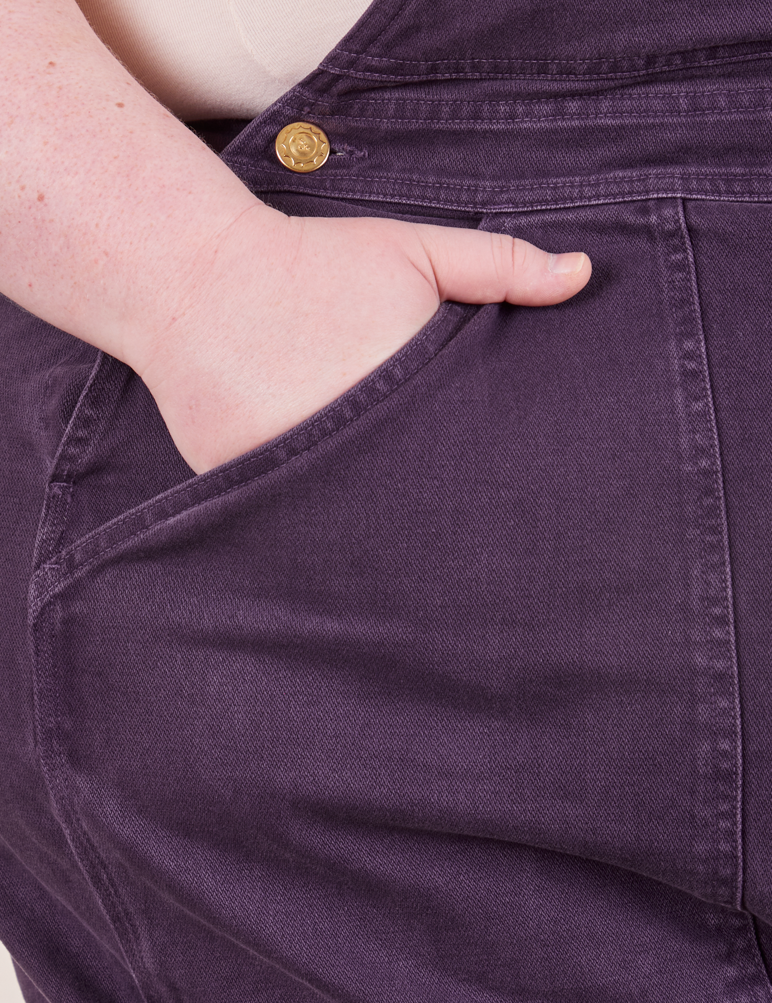 Front pocket close up of Original Overalls in Mono Nebula Purple. Catie has her hand in the pocket.