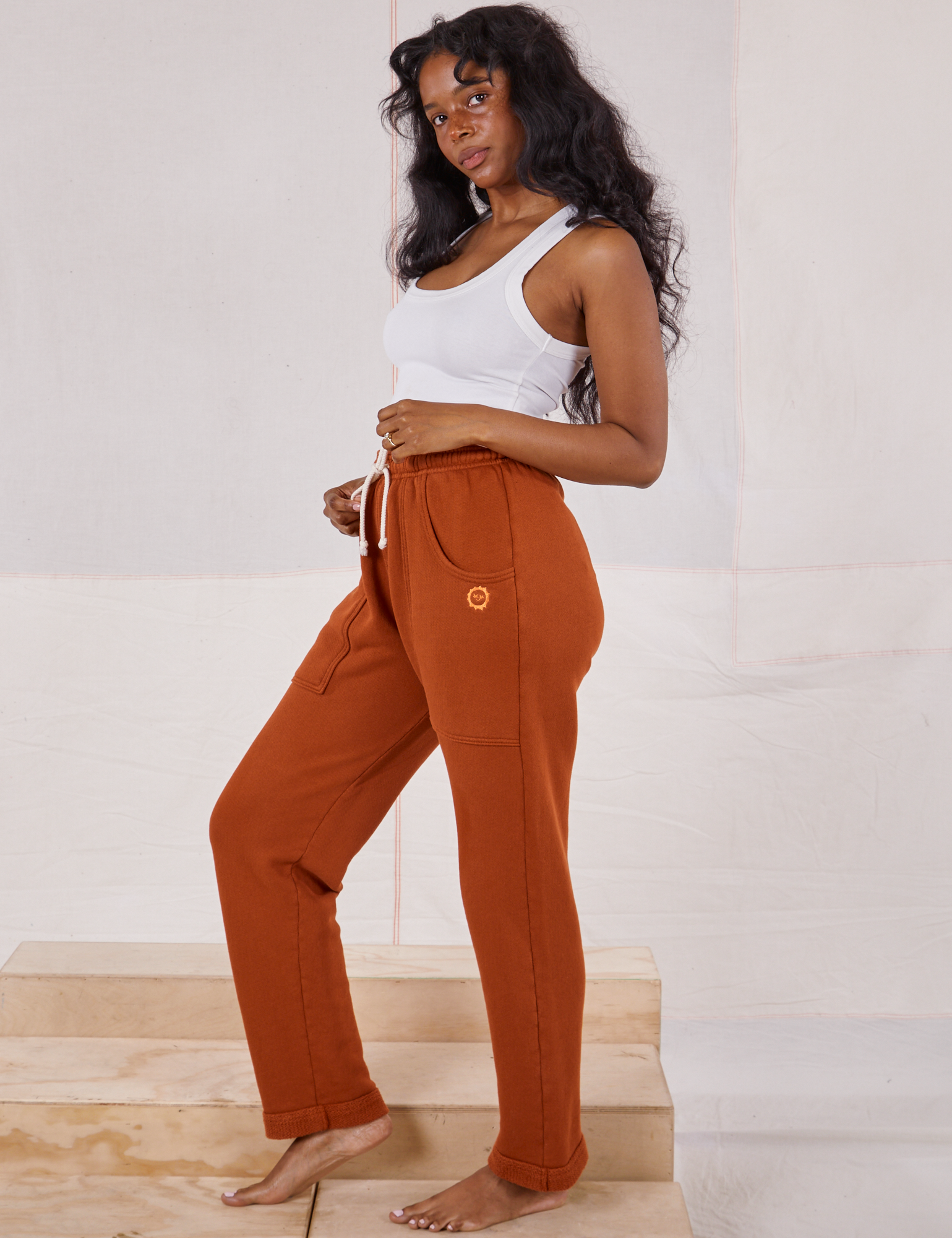 Side view of Rolled Cuff Sweat Pants in Burnt Terracotta and Cropped Tank in vintage tee off-white on Kandia