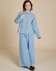 Hana is wearing a buttoned up Indigo Denim Work Jacket in Light Wash paired with light wash Indigo Wide Leg Trousers