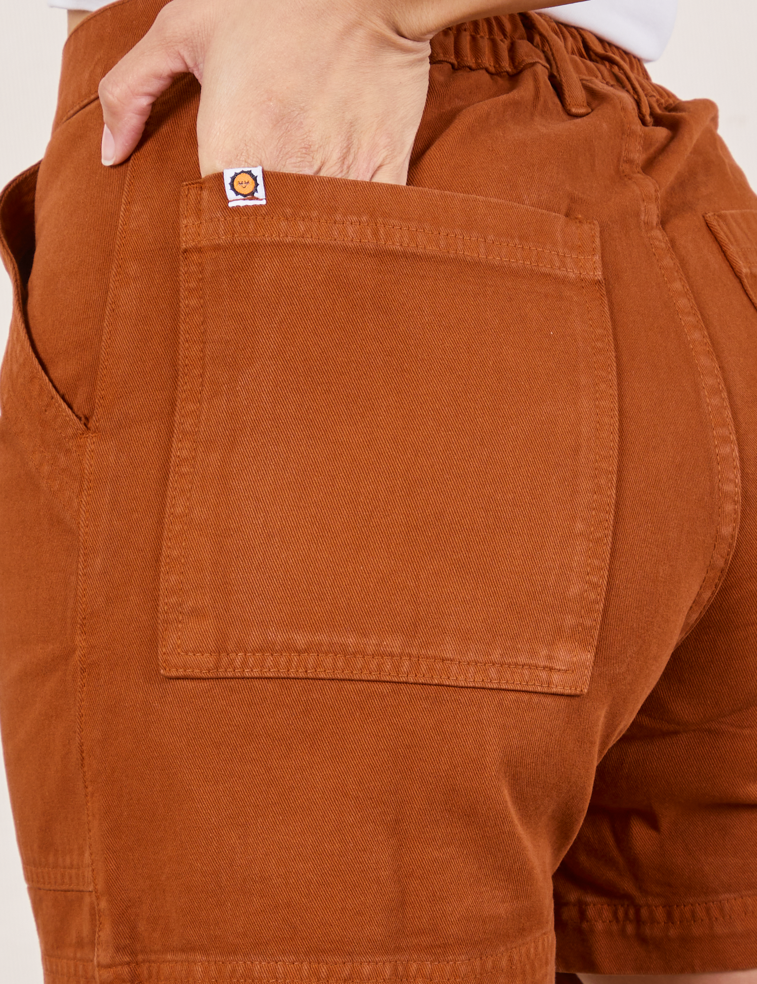 Classic Work Shorts in Burnt Terracotta back pocket close up. Tiara has her hand in the pocket.