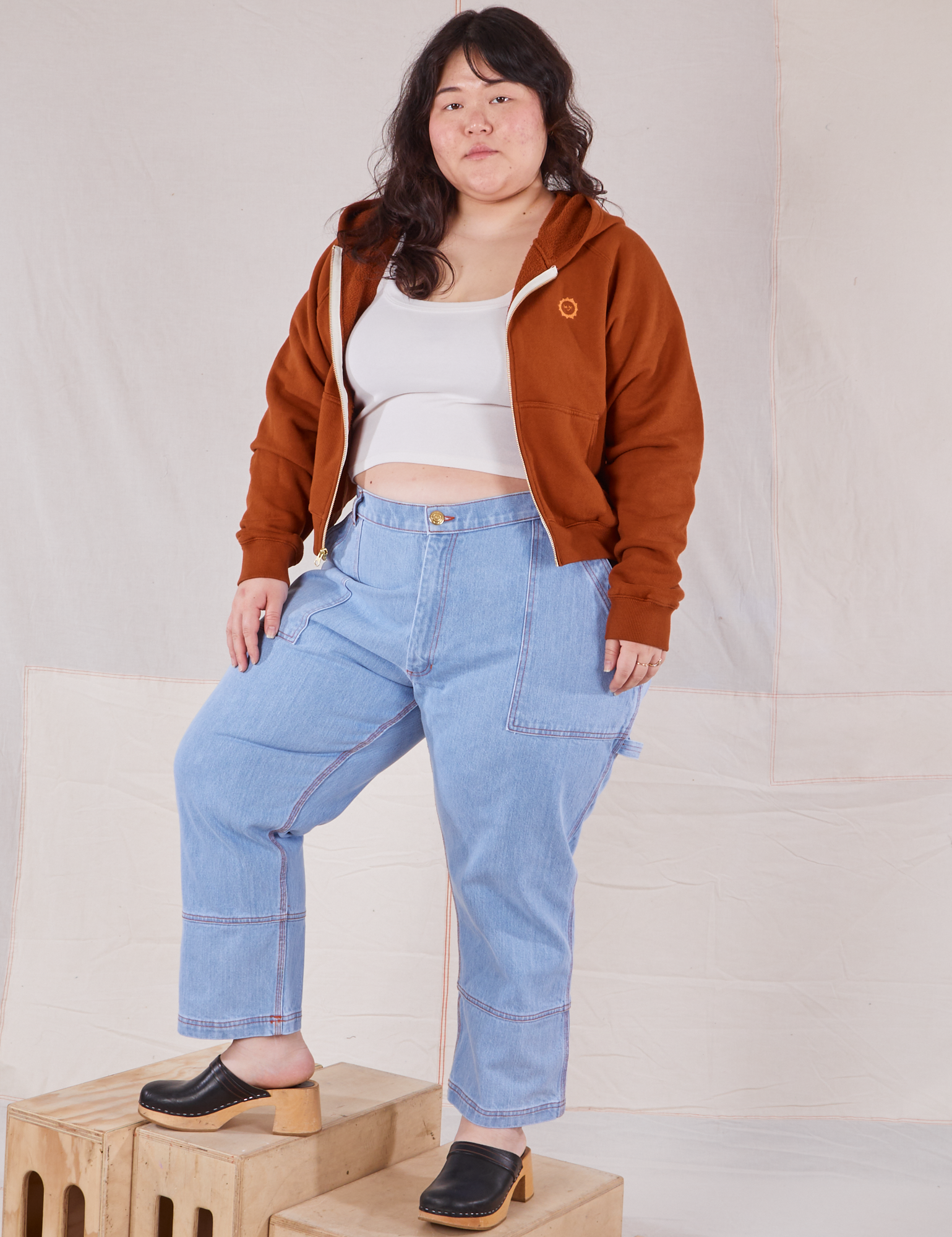 Ashley is 5&#39;7&quot; and wearing L Cropped Zip Hoodie in Burnt Terracotta paired with a vintage off-white Cropped Tank and light wash Carpenter Jeans