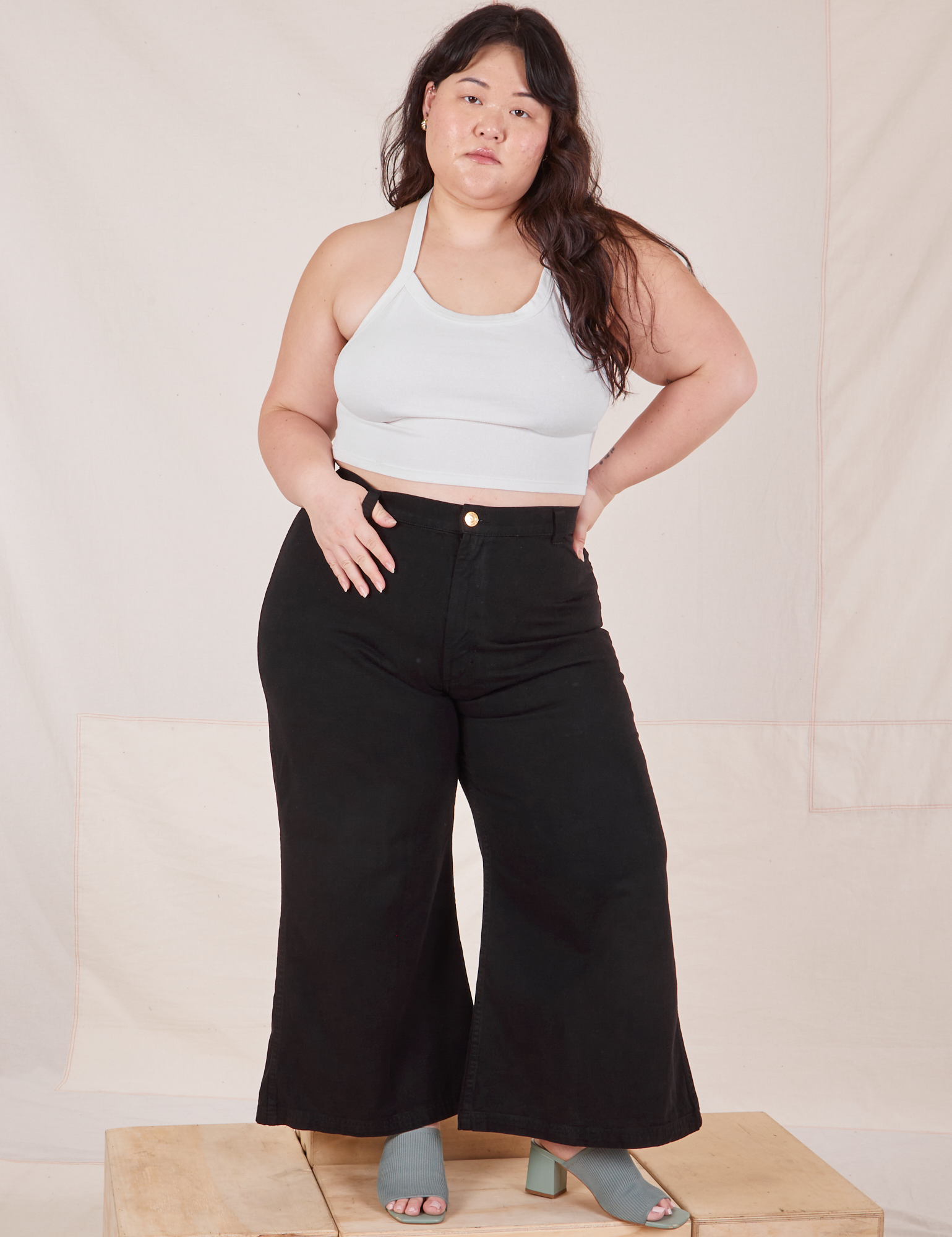 Ashley is 5&#39;7&quot; and wearing 1XL Petite Bell Bottoms in Basic Black paired with a Halter Top in vintage off-white