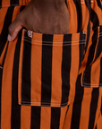 Close up of Isaac's hand in the back pocket of Black Stripe Work Pants in Construction Orange