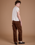 Angled back view of Carpenter Jeans in Fudgesicle Brown and Organic Vintage Tee in Vintage Tee Off-White on Quinn