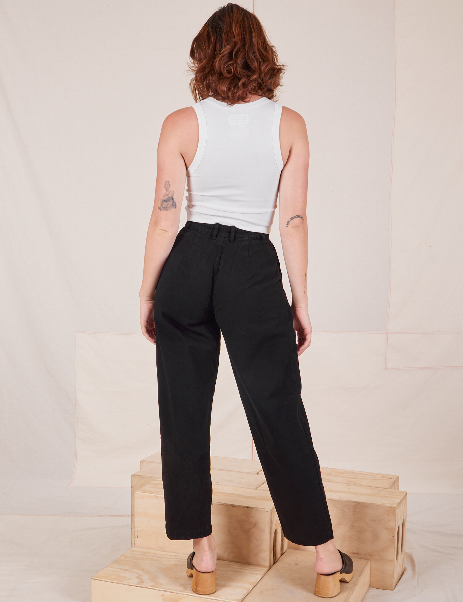 Back view of Heavyweight Trousers in Basic Black and Cropped Tank Top in vintage tee off-white worn by Alex.
