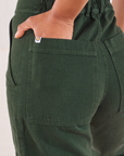 Heritage Short Sleeve Jumpsuit in Swamp Green back pocket close up. Mika has her hand in the pocket.