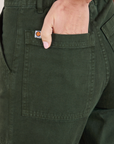 Work Pants in Swamp Green back pocket close up. Madeline has her hand in the pocket.