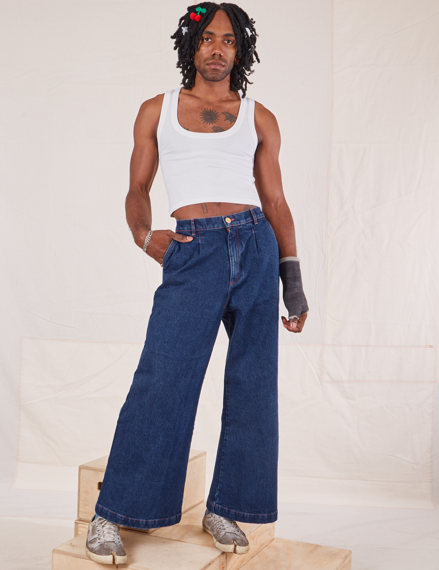Jerrod is 6'3" and wearing S Indigo Wide Leg Trousers in Dark Wash paired with vintage off-white Cropped Tank Top
