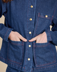 Close up of Alex's hands in both front pockets of Indigo Denim Work Jacket in Dark Wash