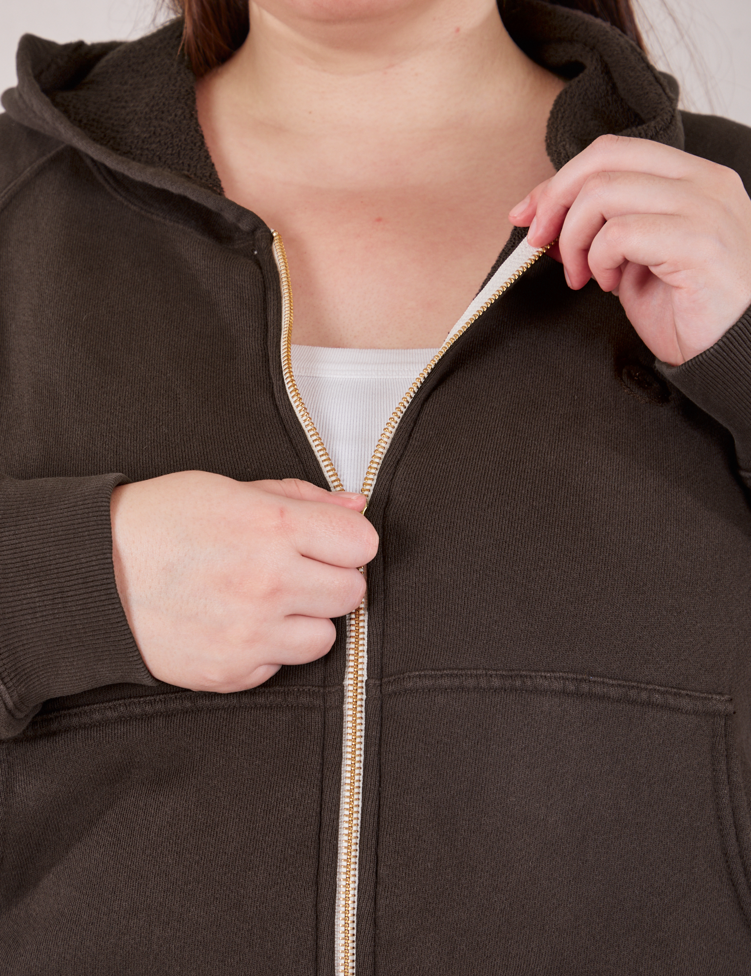 Cropped Zip Hoodie in Espresso Brown front close up. Marielena is pulling on the zipper tab.