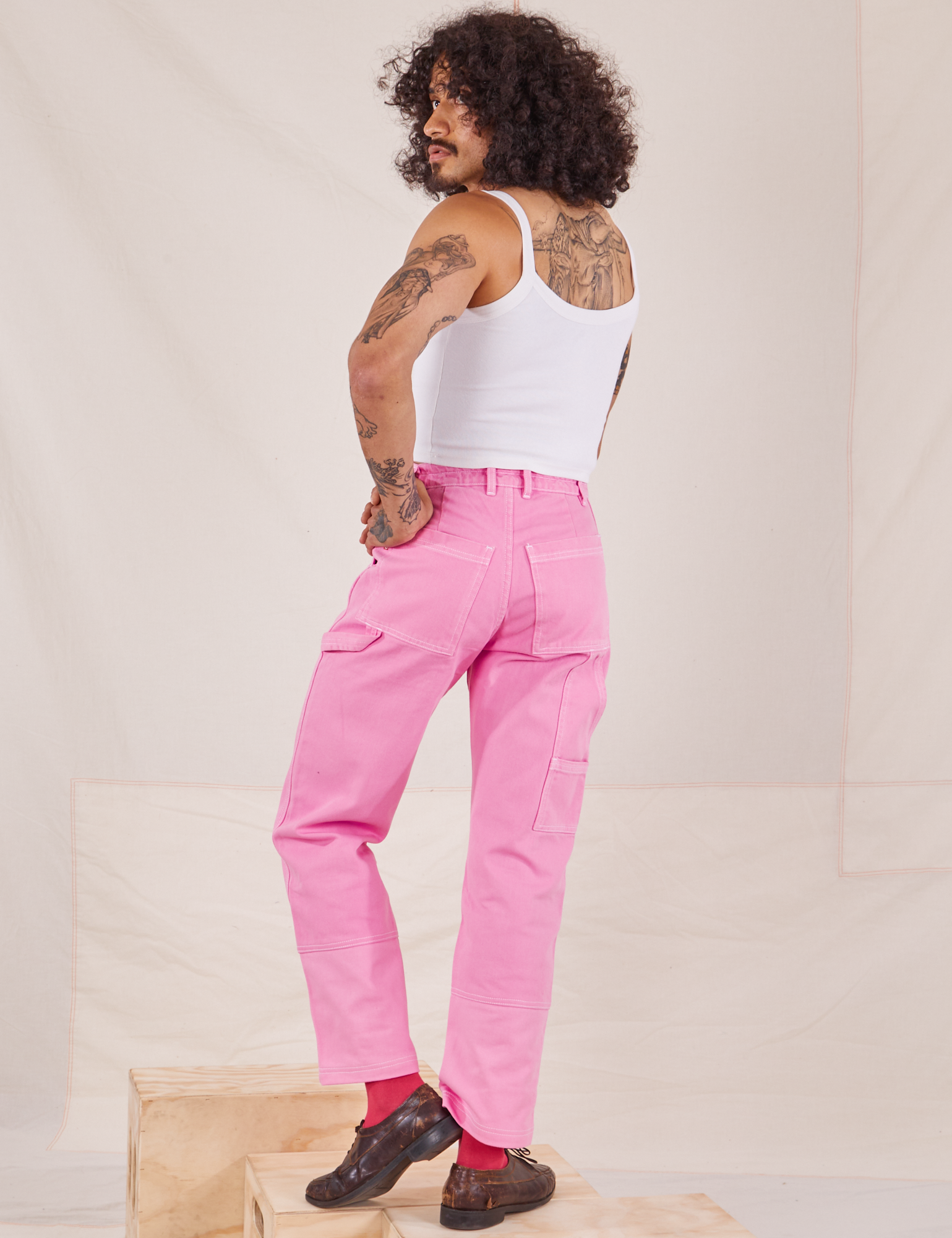 Back view of Carpenter Jeans in Bubblegum Pink and Cropped Cami in vintage tee off-white worn by Jesse