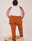 Back view of Carpenter Jeans in Burnt Terracotta and Tank Top in vintage tee off-white on Sam