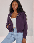 Kandia is wearing Cropped Zip Hoodie in Nebula Purple, vintage off-white Cropped Tank and light wash Carpenter Jeans