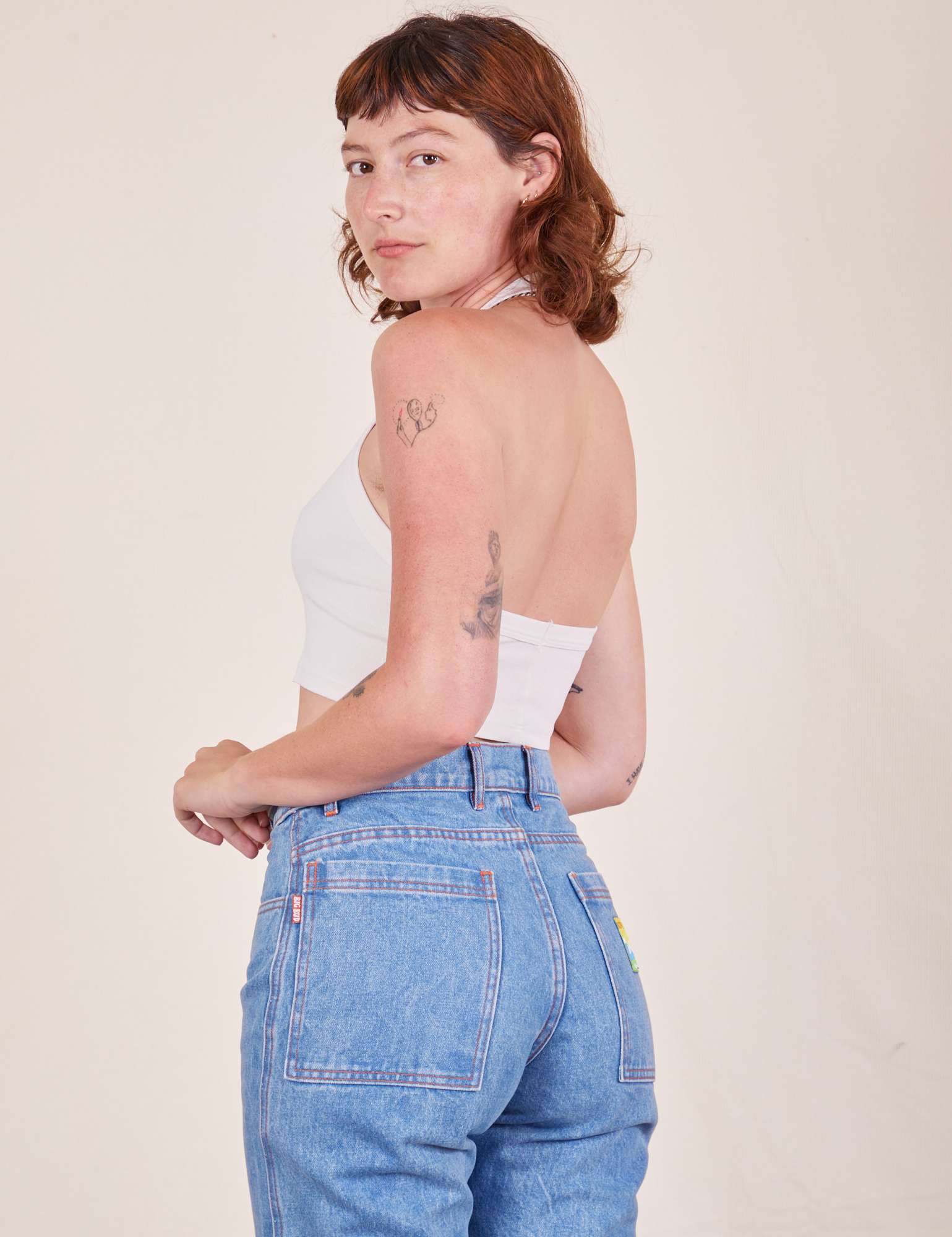 Angled back view of Halter Top in Vintage Tee Off-White and light wash Frontier Jeans worn by Alex