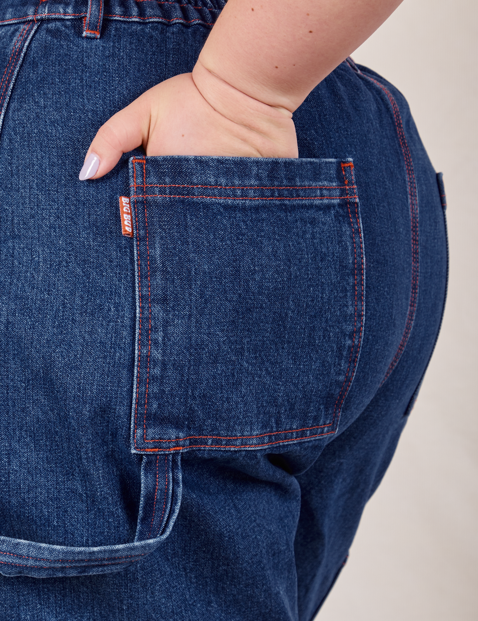 Carpenter Shorts in Dark Wash back pocket close up. Ashley has her hand in the pocket.