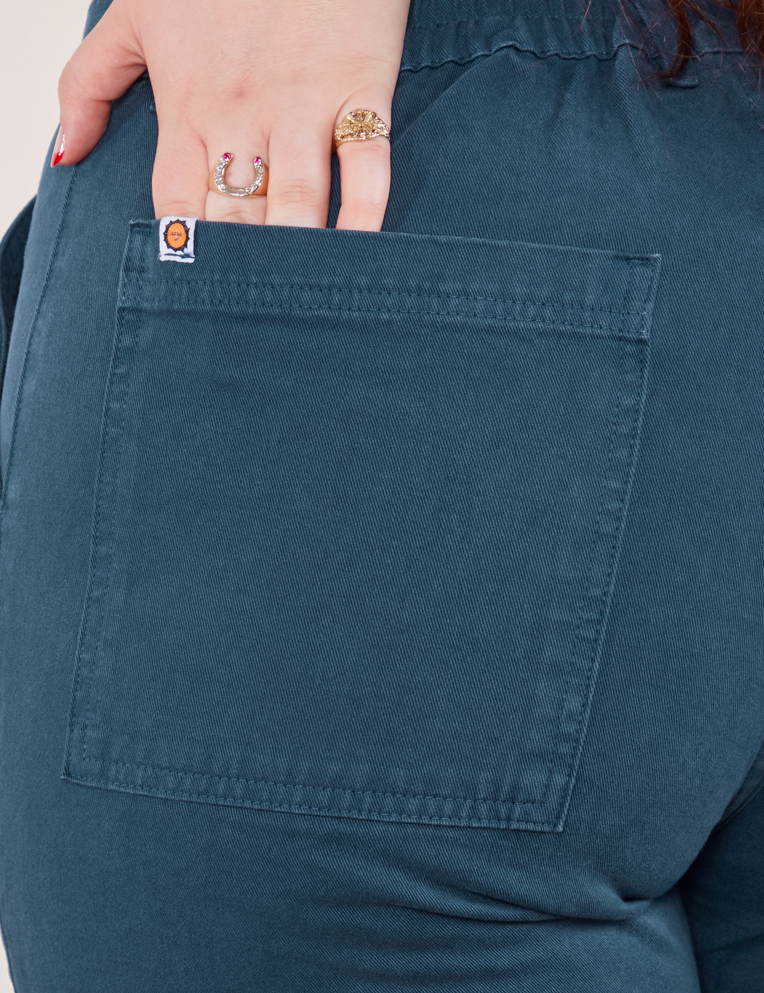 Work Pants in Lagoon back pocket close up. Sydney has her hand in the pocket.