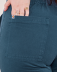 Work Pants in Lagoon back pocket close up. Sydney has her hand in the pocket.