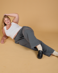 Juliet is laying down on the floor wearing Baggy Mid-Rise Trousers in Slate Grey and vintage tee white Cropped Tank