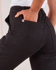 Organic Work Pants in Basic Black back pocket close up. Mika has her hand in the pocket.