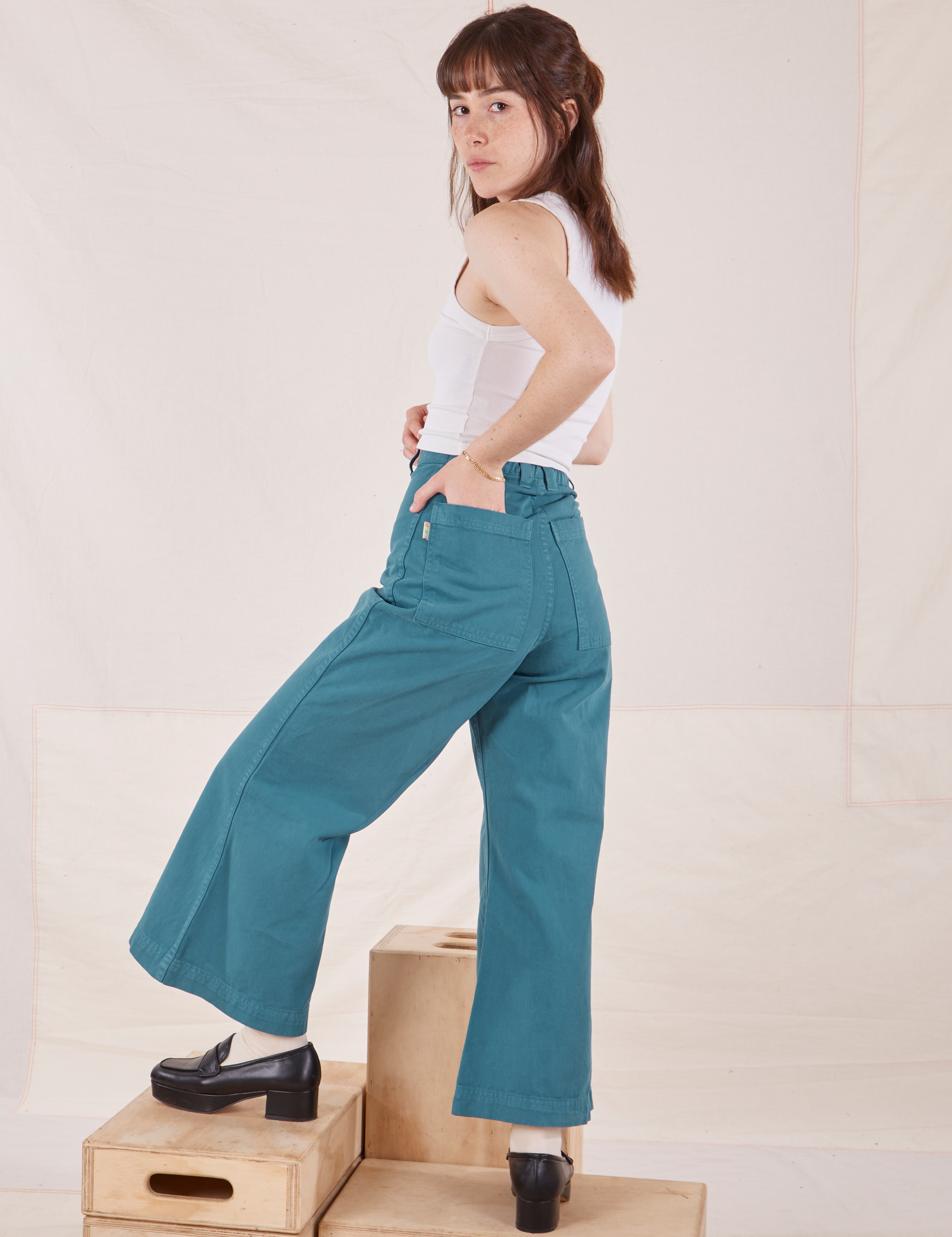 Angled back view of Petite Bell Bottoms in Marine Blue and Cropped Tank Top in vintage tee off-white on Hana
