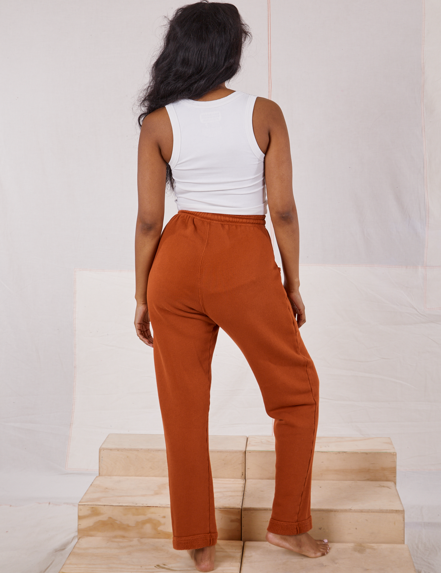 Back view of Rolled Cuff Sweat Pants in Burnt Terracotta and vintage off-white Cropped Tank on Kandia