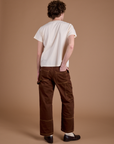 Back view of Carpenter Jeans in Fudgesicle Brown and Organic Vintage tee in Vintage Tee Off-White on Quinn