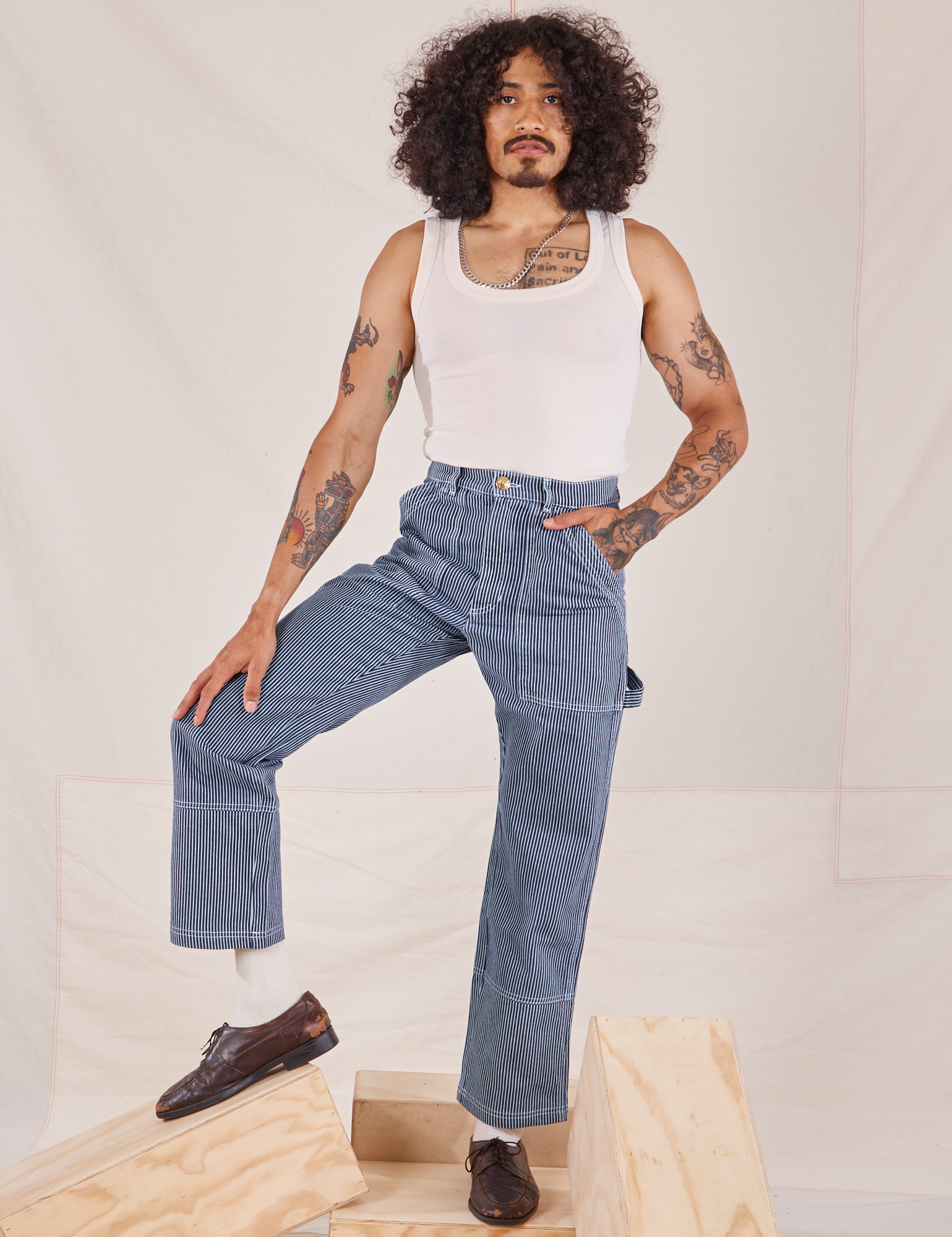 Jesse is 5&#39;8&quot; and wearing XS Carpenter Jeans in Railroad Stripes paired with Tank Top in vintage tee off-white