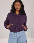 Kandia is wearing a zipped up Cropped Zip Hoodie in Nebula Purple and light wash Carpenter Jeans