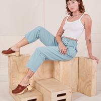 Alex is sitting on a wooden crate wearing Heavyweight Trousers in Baby Blue and vintage off-white Cropped Cami