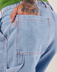 Carpenter Shorts in Light Wash back pocket close up. Jesse has their hand in the pocket.