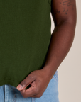 Close up of Demi holding the bottom hem of Muscle Tee in Evergreen