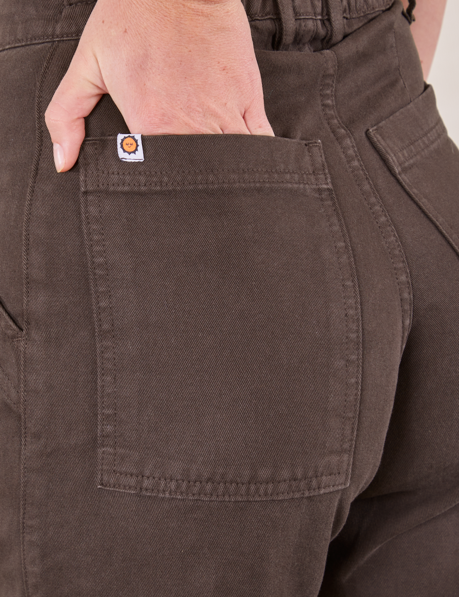 Pencil Pants in Espresso Brown back pocket close up. Scarlett has her hand in the pocket.